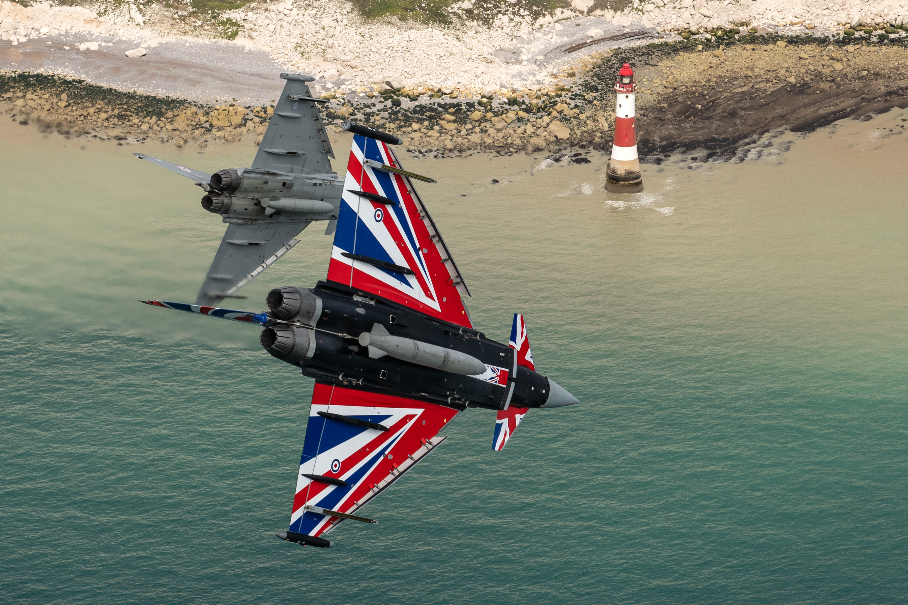Image shows two Typhoons with Union Jack paint in flight over the white cliffs.
